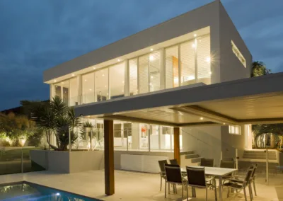 Modern house at dusk with swimming pool and barbecue in backyard